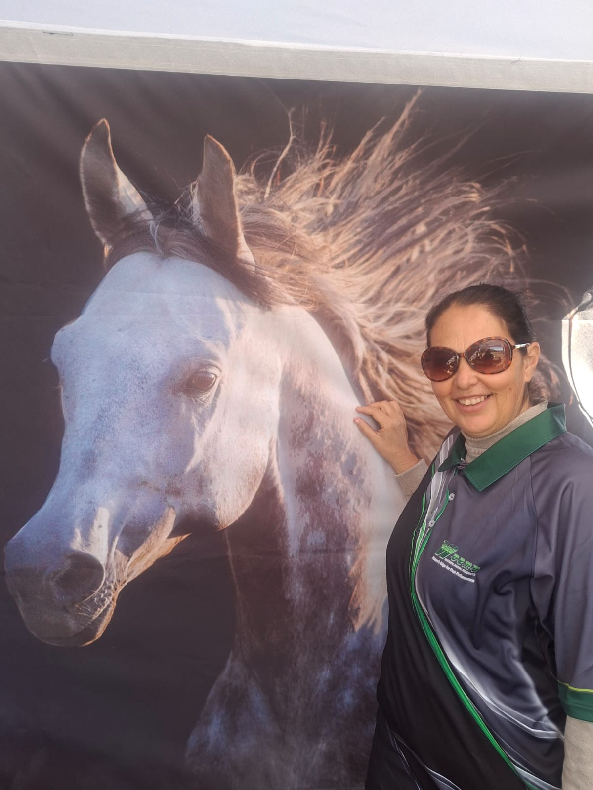 A WOEMA team member posing beside the white horse backdrop at the Fauresmith 2026 stand