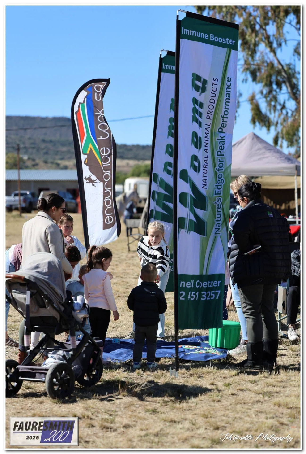 Children gathered around a game mat beside the WOEMA banners at Fauresmith 2026
